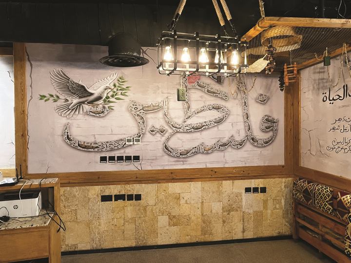 Restaurant wall with large sculpted Arabic lettering and a painted dove carrying an olive branch