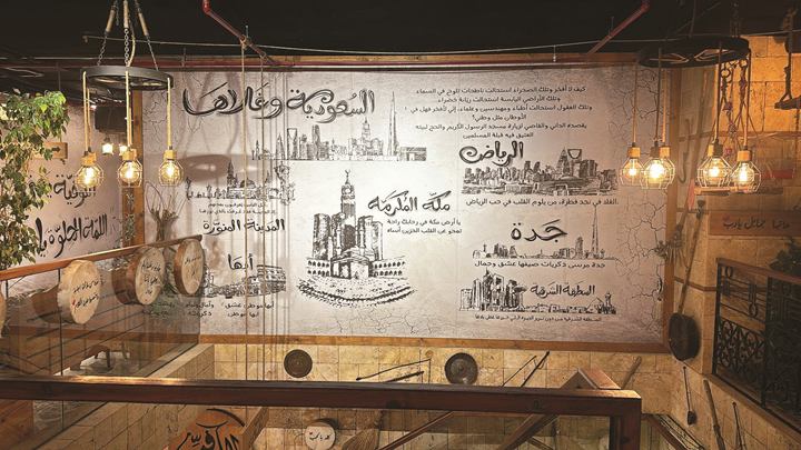 Restaurant wall with hand-drawn Saudi city skylines and landmarks and Arabic calligraphy, framed in wood