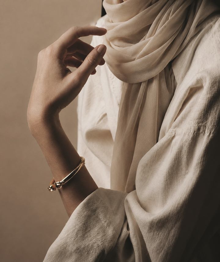 Portrait from the SALLY NAJJAR company profile: hands and a cream silk scarf in soft light